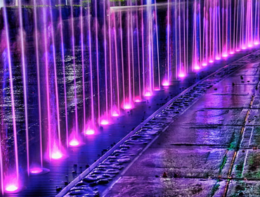 A beautifully lit fountain featuring vibrant purple lights, with water flowing elegantly