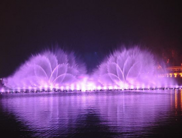 A large fountain illuminated by lights, featuring vibrant purple water cascading elegantly